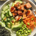 Healthy high protein salmon meal prep bowl with fresh vegetables and teriyaki sauce
