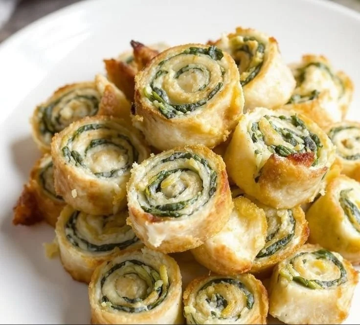 Bite-sized pinwheels filled with creamy spinach dip served on a platter.