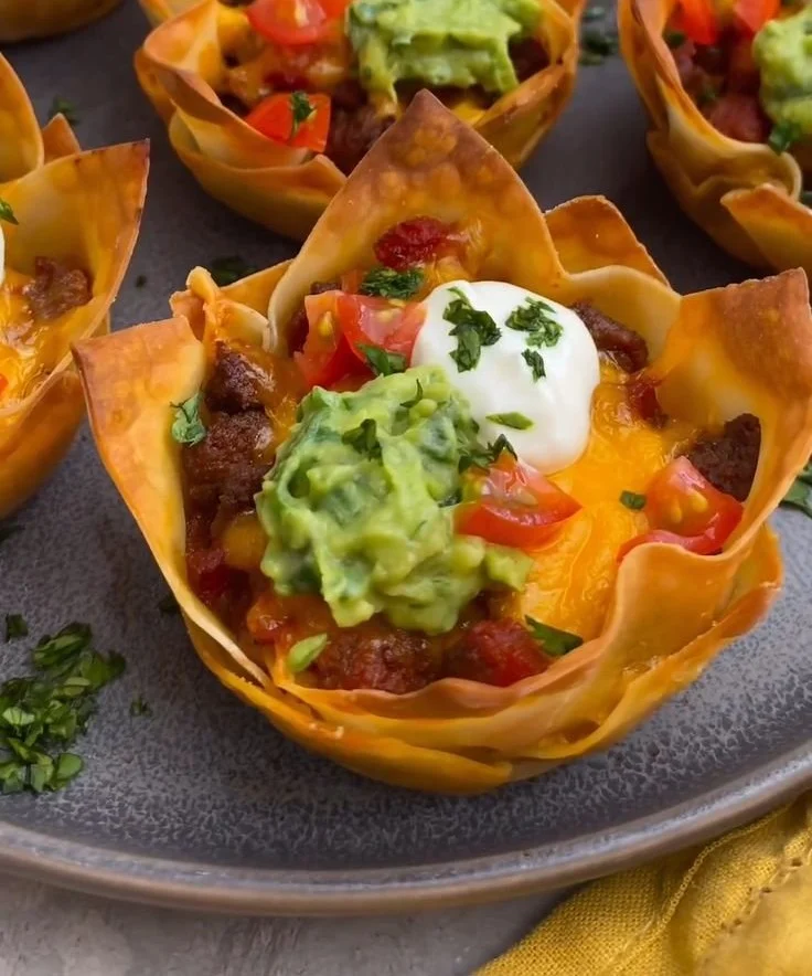 A platter of delicious homemade taco cups filled with toppings and garnishes.