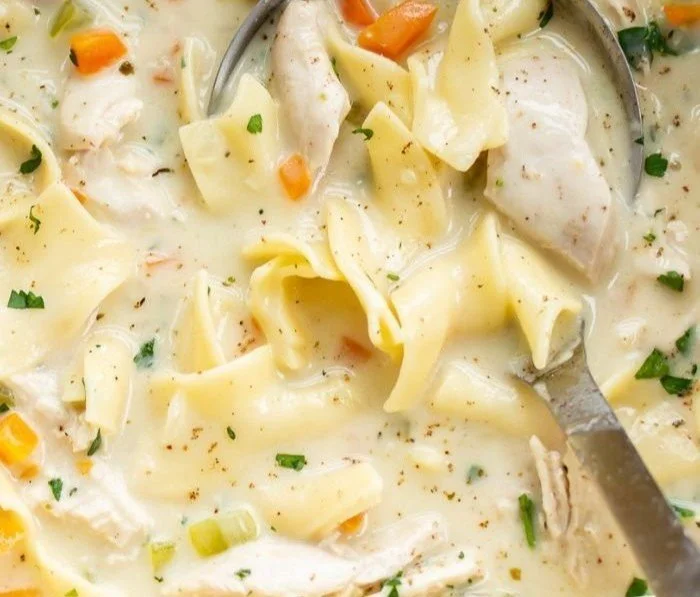 Bowl of creamy chicken soup with vegetables and herbs
