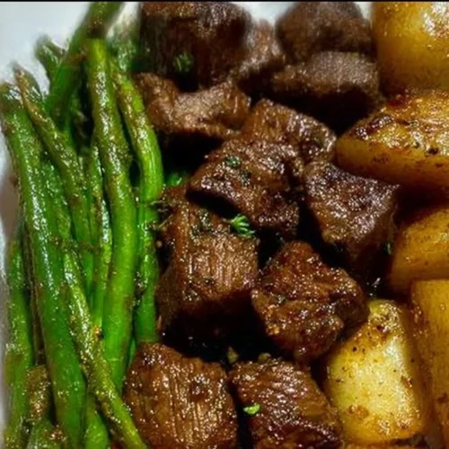 Delicious garlic balsamic steak bites garnished with herbs on a wooden platter.
