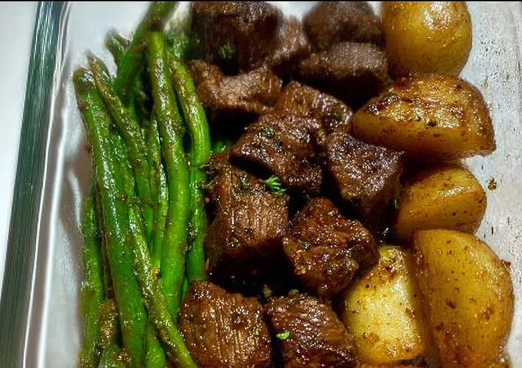 Delicious garlic balsamic steak bites garnished with herbs on a wooden platter.