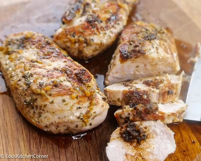 Garlic Butter Baked Chicken Breasts served with herbs and side vegetables.