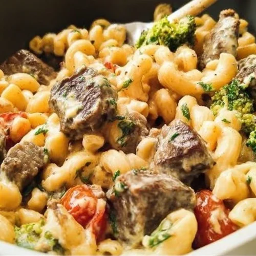 Plate of creamy steak pasta garnished with herbs and served with parmesan cheese.