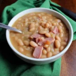 Bowl of slow cooker ham and bean soup topped with parsley.