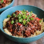 Spicy sesame ground beef and quinoa bowls topped with fresh vegetables.